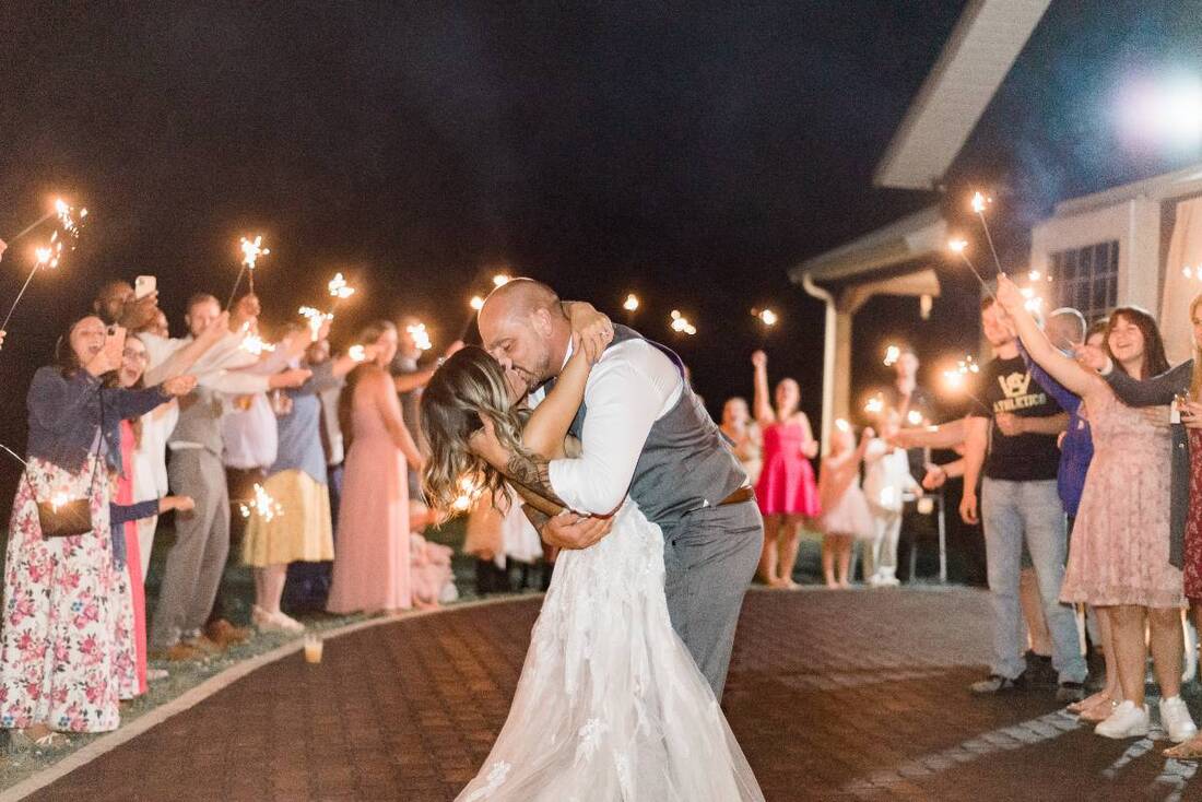 A newly-married bride and groom kissing during their sparkler sendoff at a Knoxville barn wedding venue