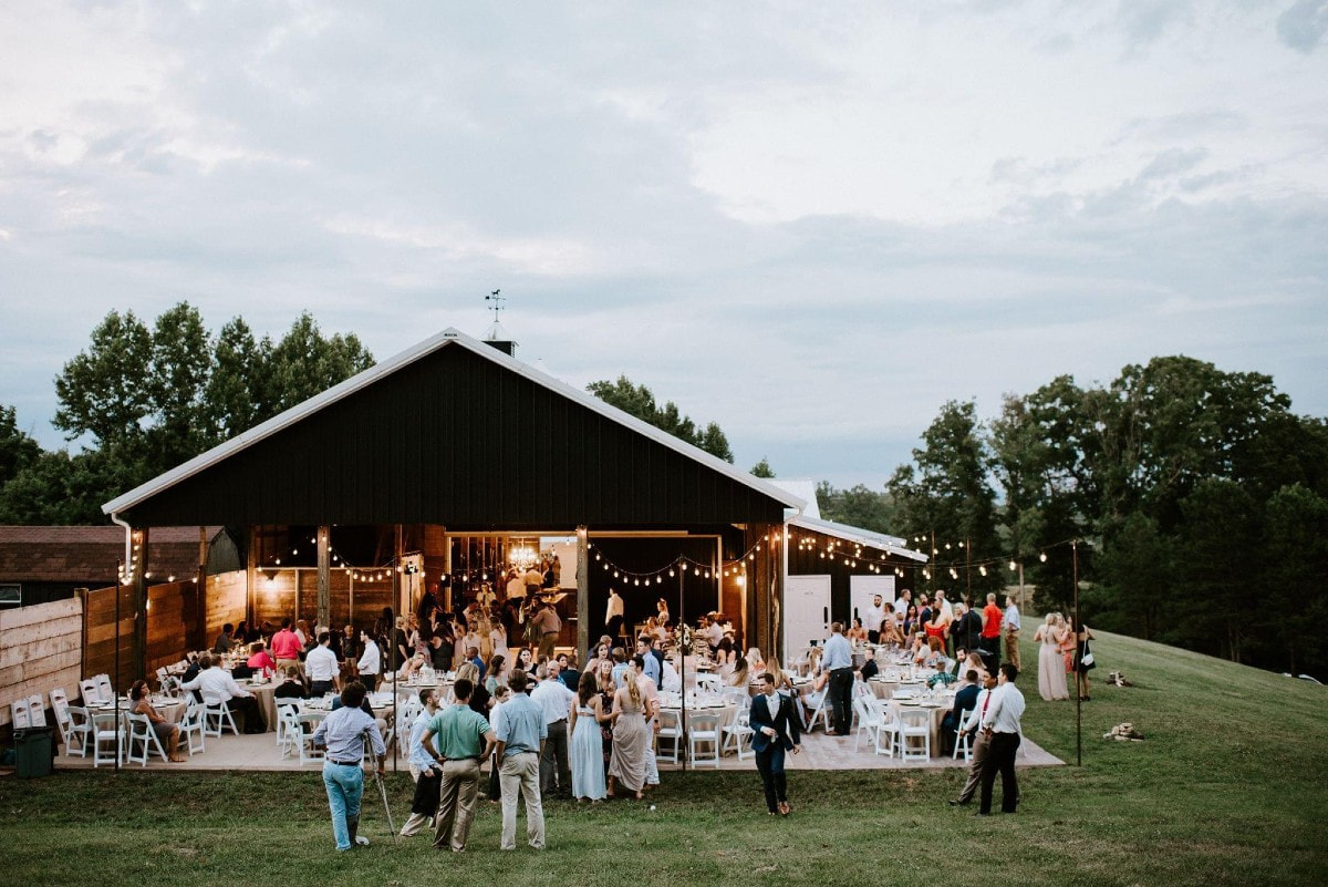 People enjoying an outdoor reception at a barn wedding venue in Knoxville on a cloudy day